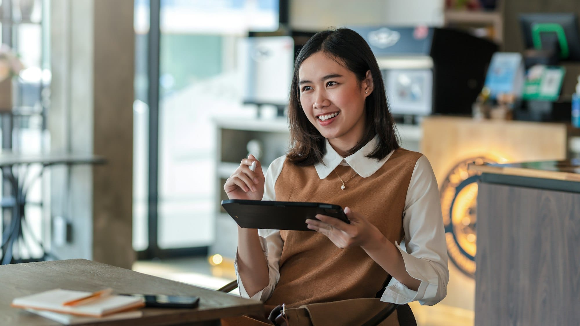 Beautiful smiling happy businesswoman holding a stylus with a tablet at café with Google Review Management Service Malaysia