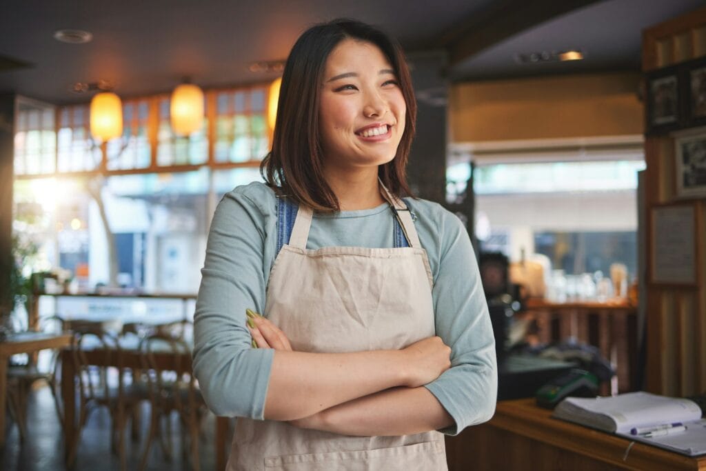 Smile, thinking and arms crossed with an asian woman in a restaurant working as a waitress for serv with Google Review Management Service Malaysia